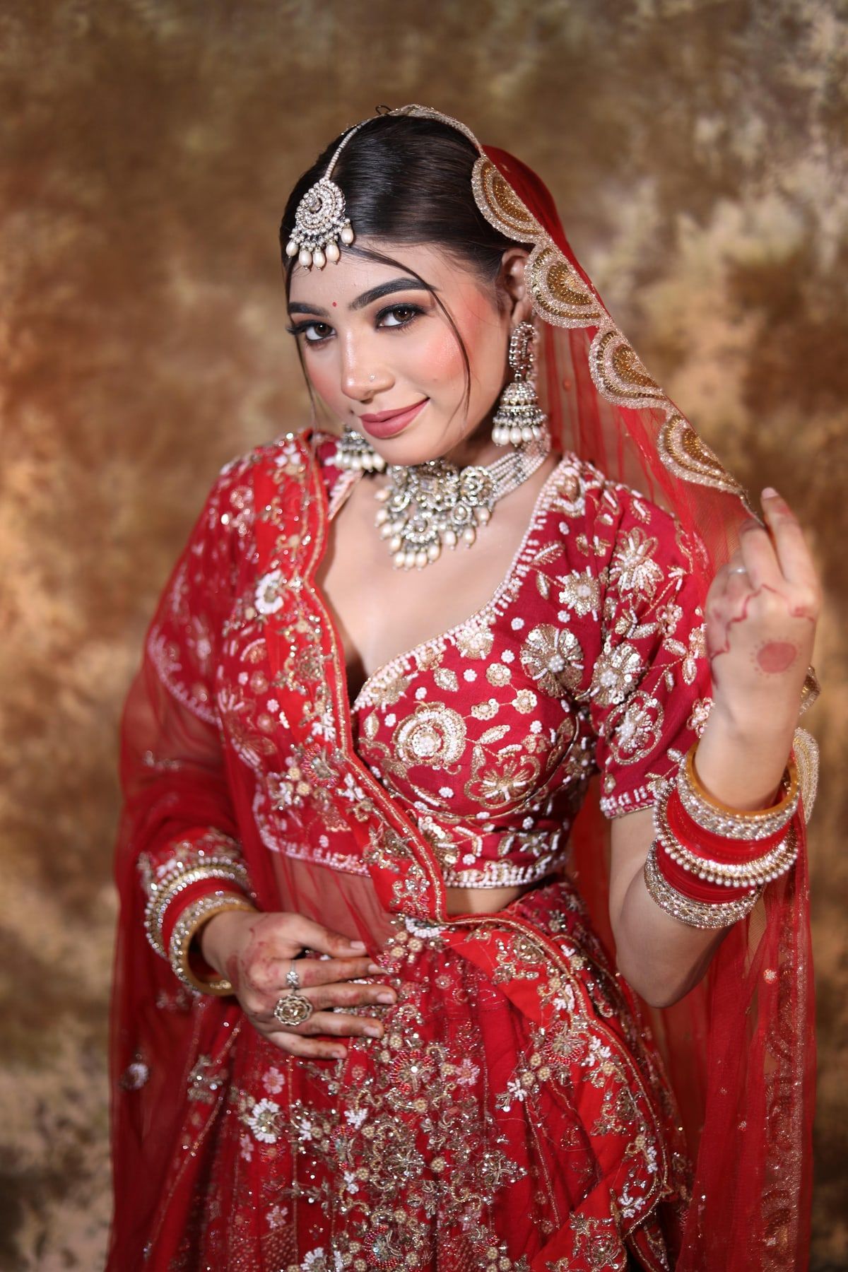 Bride in red lehenga with HD bridal makeup and maang tikka by GlamParul